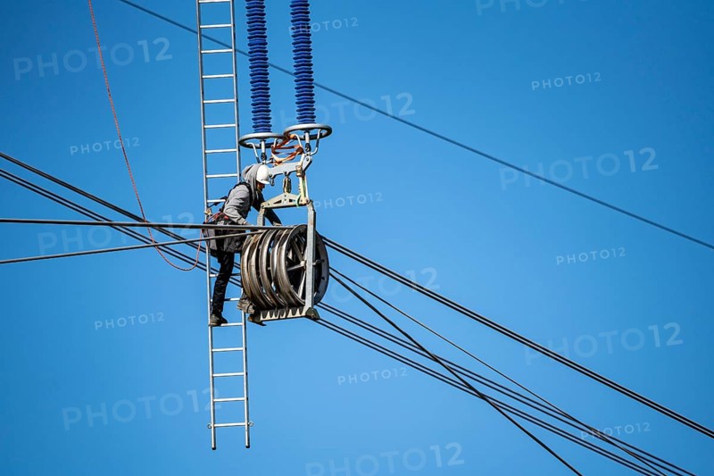 Construction of a new line route, 380 KV extra-high voltage line between Osterath and Gohr, near Neuss, fitter on ladder at great height, tensioning the lines, North Rhine-Westphalia, Germany, Europe