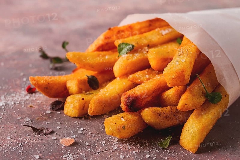 Fried French fries, in a paper bag, on an abstract background, no people, rustic