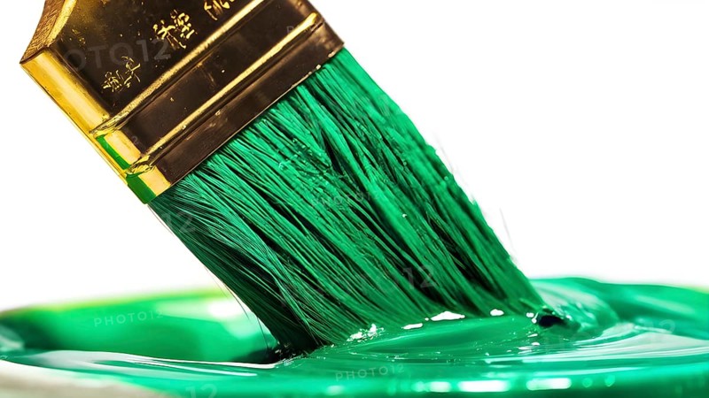 Thick paintbrush dipped in green bristles dripping onto a white background, AI generated