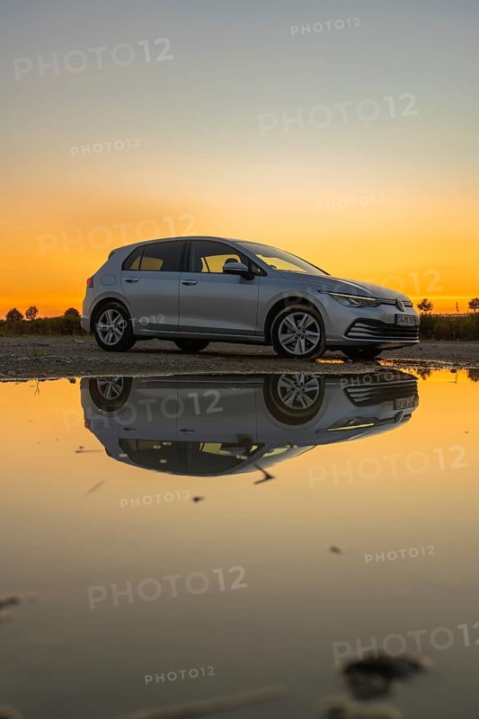 Silver car reflected in a puddle of water at sunset, atmospheric sky in shades of yellow and orange, VW Golff Diesel, Calw, Black Forest, Germany, Europe