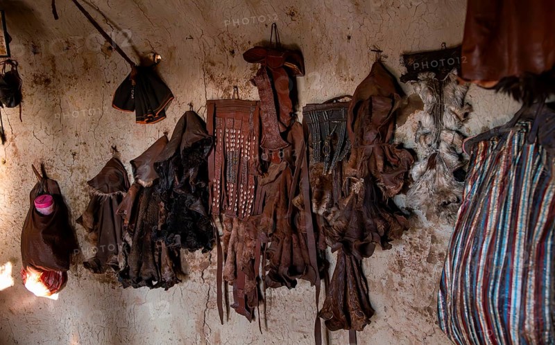 Various traditional leather aprons hanging on the wall, interior of a mud hut of the first woman in a Himba village, near Opuwo, Kaokoveld, Kunene, Namibia, Africa