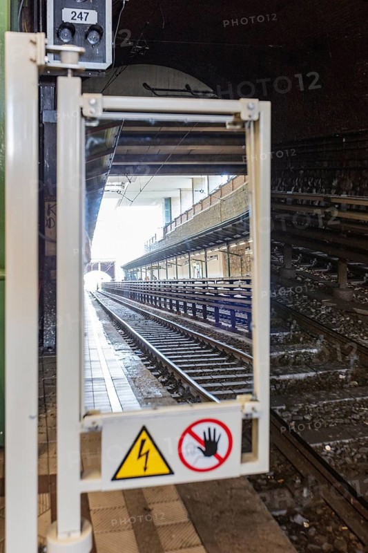 View through mirror onto railway tracks in tunnel with electricity warning sign, Vienna