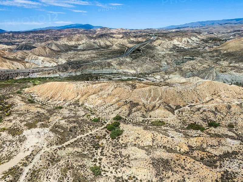 Dry desert landscape with rugged hills and a road under a clear sky, Aerial view, Tabernas Desert, Desierto de Tabernas, Tabernas, Almeria, Andalusia, Spain, Europe