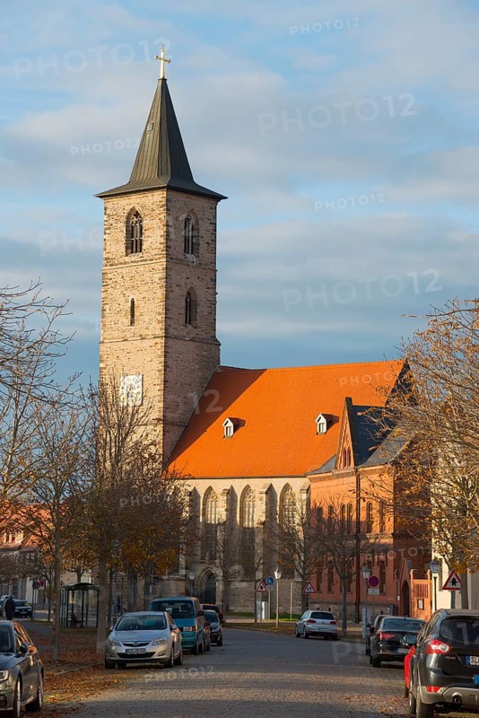 A church with a stone tower and red roof, surrounded by cars and bare trees on a road, St Nikolai Church, Bernburg an der Saale, Saxony-Anhalt, Germany, Europe