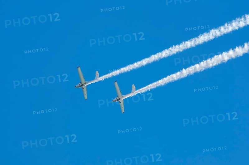 Stunt aerobatic plane performing stunts in blue sky with smoke trail. Concept of teamwork, collaboration, coordination, trust, precision, difficulty, challenge, speed, synergy