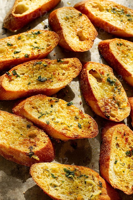 Baguette toasts, baked in the oven, with garlic butter and herbs, homemade, on a platter, top view
