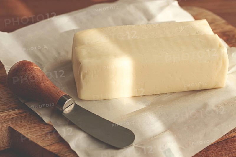 Butter briquette, on wrapping paper, wooden chopping board and butter knife, breakfast, rustic style, no people