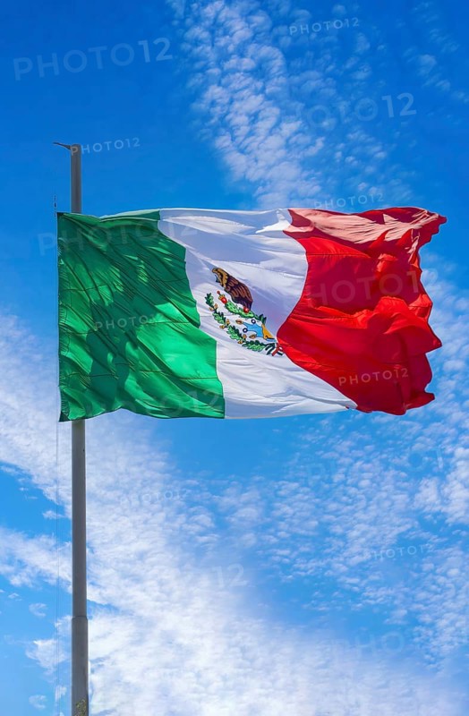 Los Cabos, Mexico, Mexican tricolor national striped flag proudly waving at mast in the air with Aztec symbol for Tenochtitlan, Central America