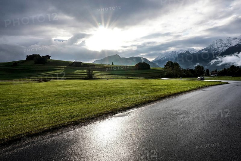 After a rain shower, the sun appears for a moment in the otherwise cloudy sky in front of the mountain backdrop in Pfronten, 13 October 2021