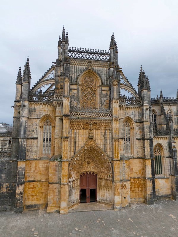 Impressive Gothic cathedral with richly decorated lancet windows and rich details on the stone-coloured façade under a cloudy sky, aerial view, monastery, Mosteiro de Santa Maria da Vitória, 'unfinished chapels', UNESCO World Heritage Site, Batalha, Leiria, Estremadura, Portugal, Europe