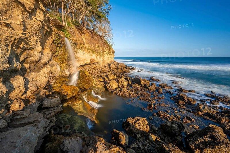 Waterfall falls into the sea on the cliffs, Catarata el Chorro, coastal landscape in the evening light, long exposure, Playa Cocalito, Pacific coast, Nicoya Peninsula, Puntarenas province, Costa Rica, Central America