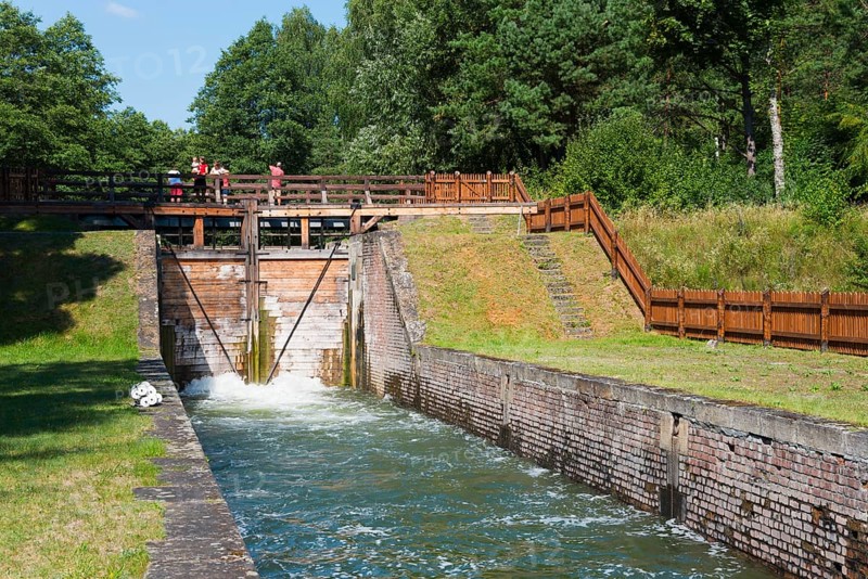 Brick and wooden sluice with people and surrounding greenery in a summer atmosphere, Sluza Paniewo, sluice between the lakes Paniewo and Krzywe, Plaska, Powiat Augustowski, Podlaskie Voivodeship, Poland, Europe
