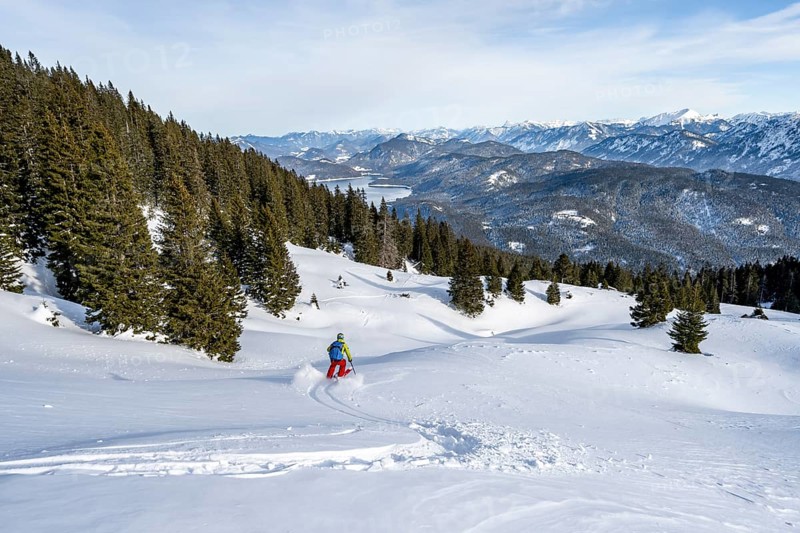 Skiers skiing down the Simetsberg, view of Walchensee and mountain panorama, Estergebirge, Bavarian Prealps, Bavaria Germany