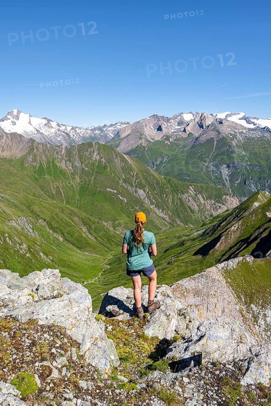 Mountaineer sitting on a rock in front of a mountain panorama with Großvenediger, mountain landscape with mountain peaks of the Venediger group, view from the summit of the Gösleswand, Lasörling group, Hohe Tauern National Park, East Tyrol, Tyrol, Austria, Europe