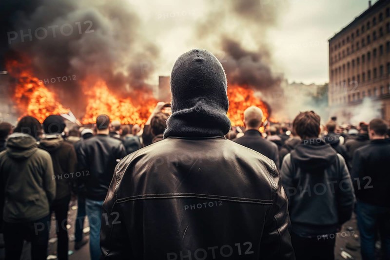 Back view of young men in street riot with fire burning in city. KI generiert, generiert AI generated