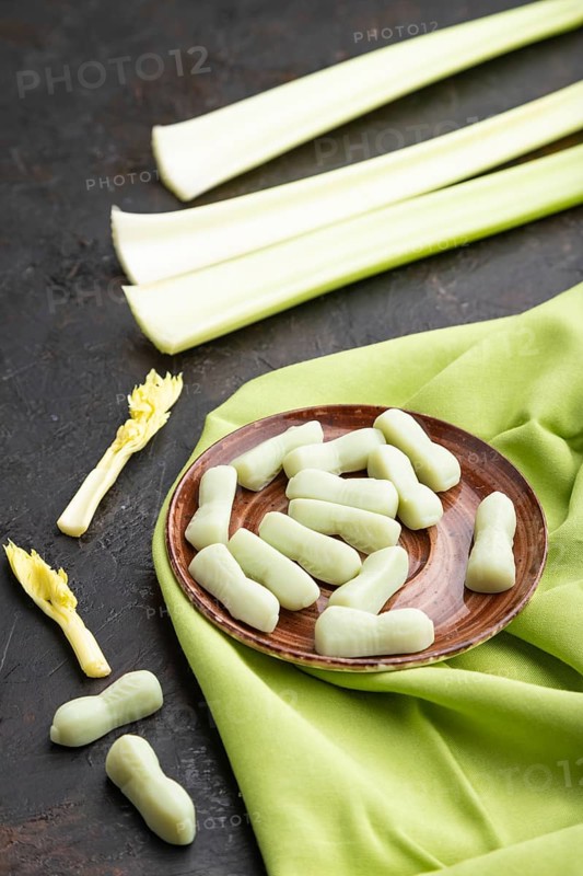 Jelly celery candies on black concrete background and green linen textile. close up, side view