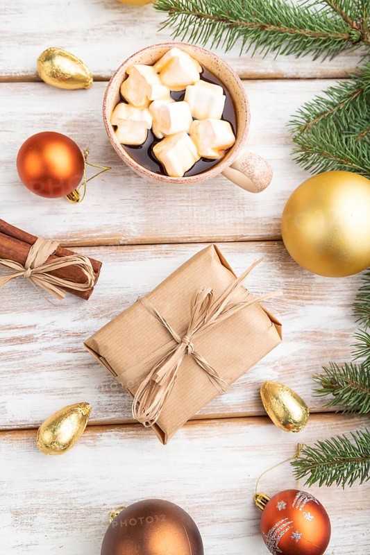 Christmas or New Year composition. Decorations, box, golden balls, cinnamon, fir and spruce branches, cup of coffee, on a white wooden background. Top view, close up, flat lay