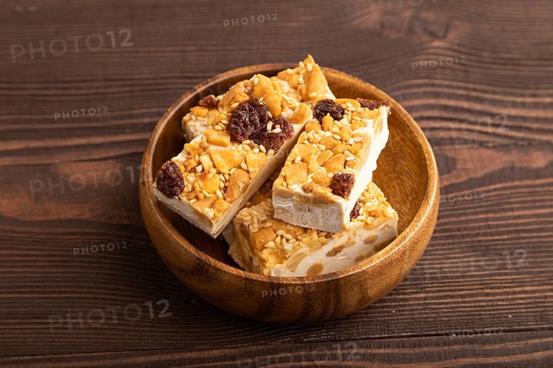 Traditional candy nougat with nuts and sesame on brown wooden background. side view, close up