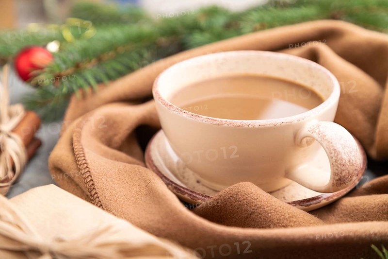 Christmas or New Year composition. Decorations, box, cinnamon, fir and spruce branches, cup of coffee, wool scarf on a gray concrete background. Side view, close up, selective focus