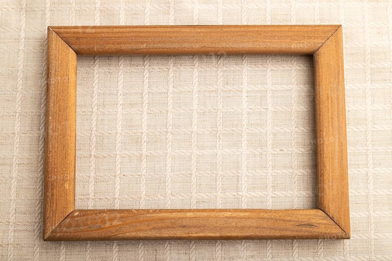 Wooden frame on smooth white linen tissue. Top view, flat lay, natural textile background and texture