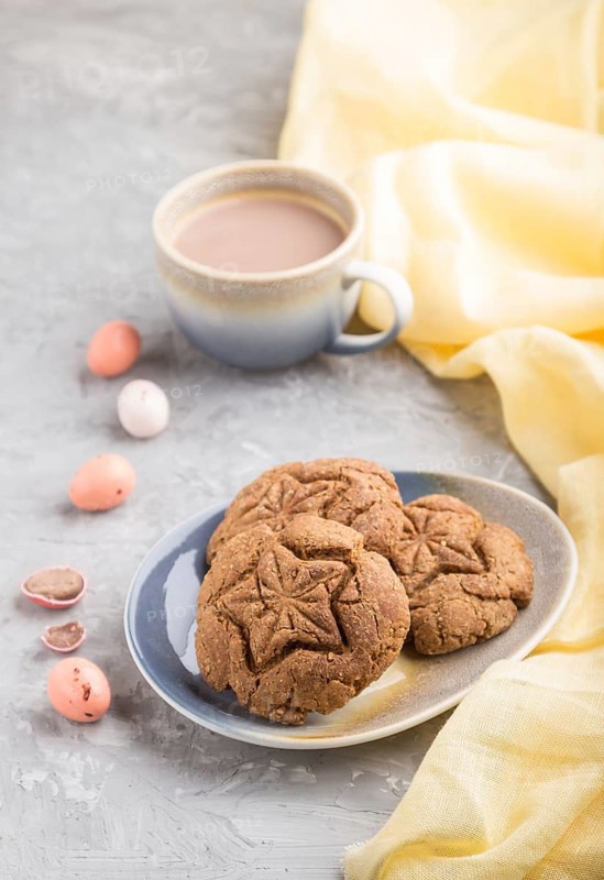 Homemade oatmeal cookies with a cup of cocoa and a yellow textile on a gray concrete background. side view, close up, selective focus