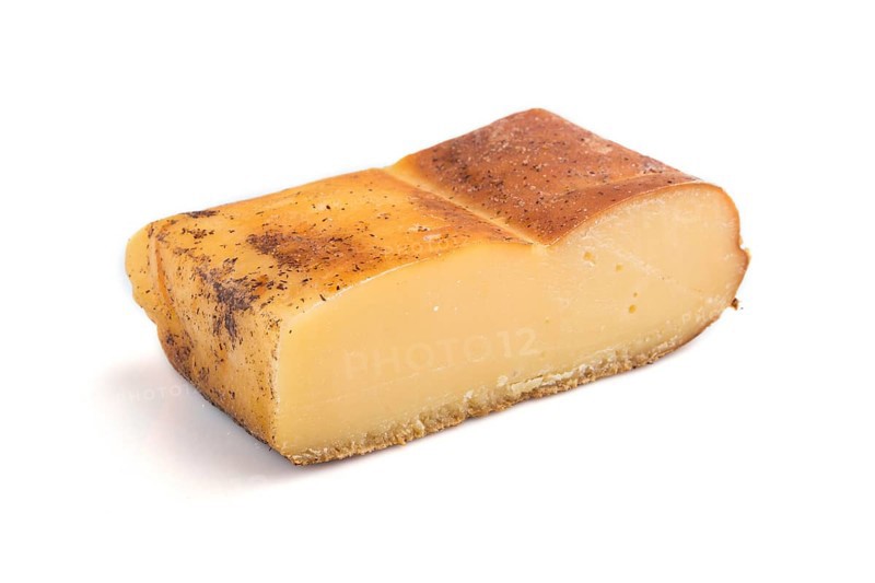 Piece of smoked cheese isolated on white background. Side view, close up