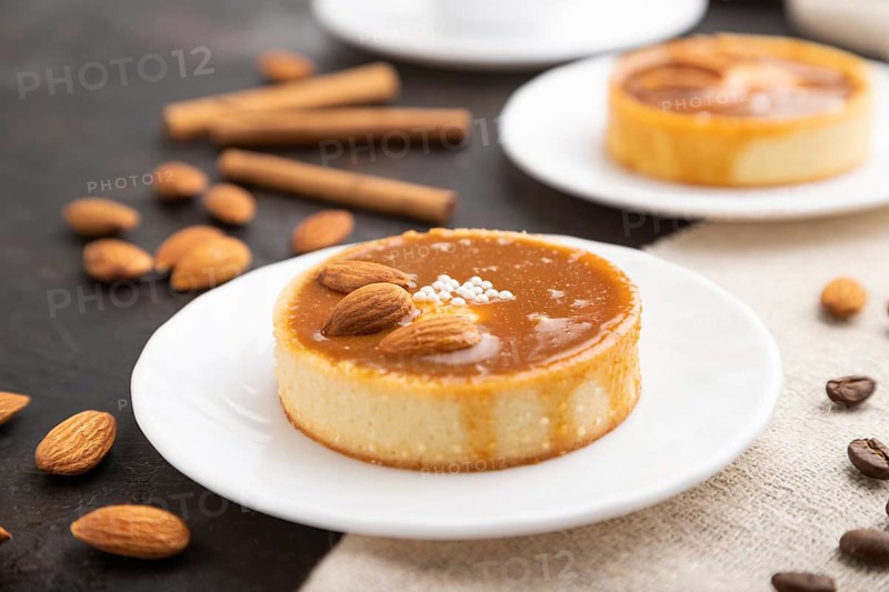 Sweet tartlets with almonds and caramel cream with cup of coffee on a black concrete background and linen textile. Side view, close up, selective focus
