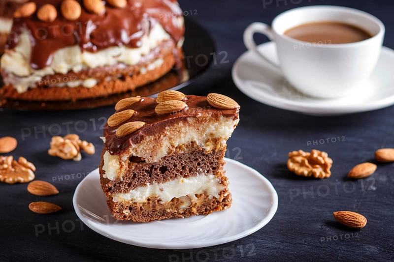 Homemade chocolate cake with milk cream, caramel and almonds on black wooden background. cup of coffee, close up