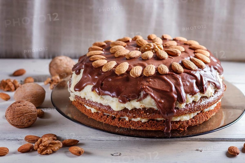 Homemade chocolate cake with milk cream and almonds on white wooden background. close up