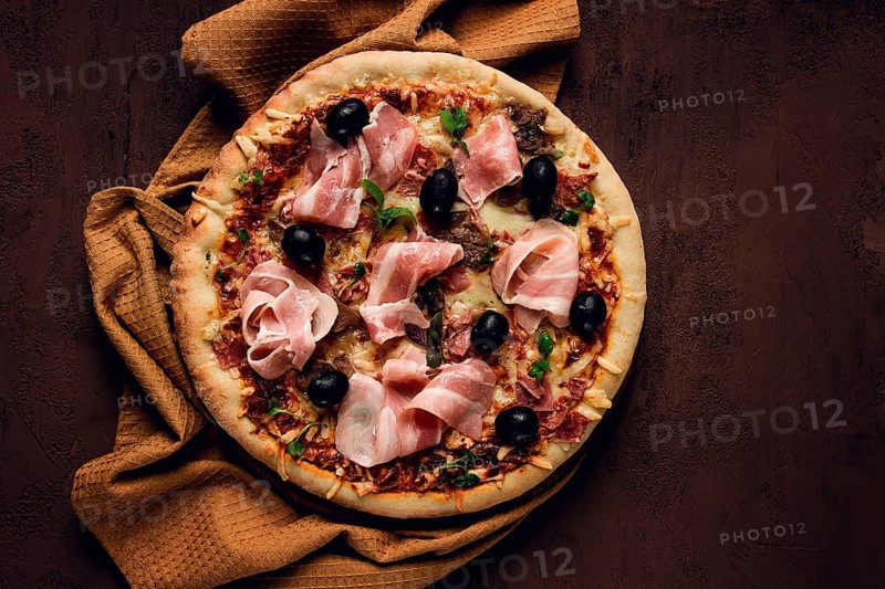 Pizza with prosciutto and mushrooms, bacon, olives, homemade, top view, no people