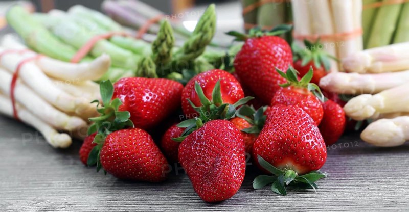 Green asparagus, white asparagus and fresh strawberries decorated on a rustic wooden table