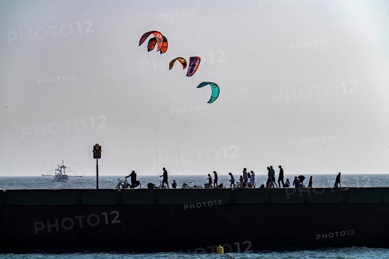 Kitesurfer off the coast of Scheveningen, walkers on the harbour pier, The Hague, Netherlands