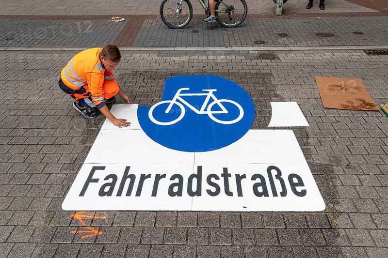 Application of road markings for a cycle lane, Rüttenscheider Straße in Essen, in the shopping and gastronomy district, cyclists have right of way over motorised vehicles, part of a cycle axis through Essen's city centre