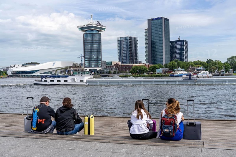 Tourists sitting at the back of Amsterdam Centraal railway station, on the promenade of the river Ij, A'DAM Lookout, skyscraper, sight, This is Holland, Amsterdam, Netherlands