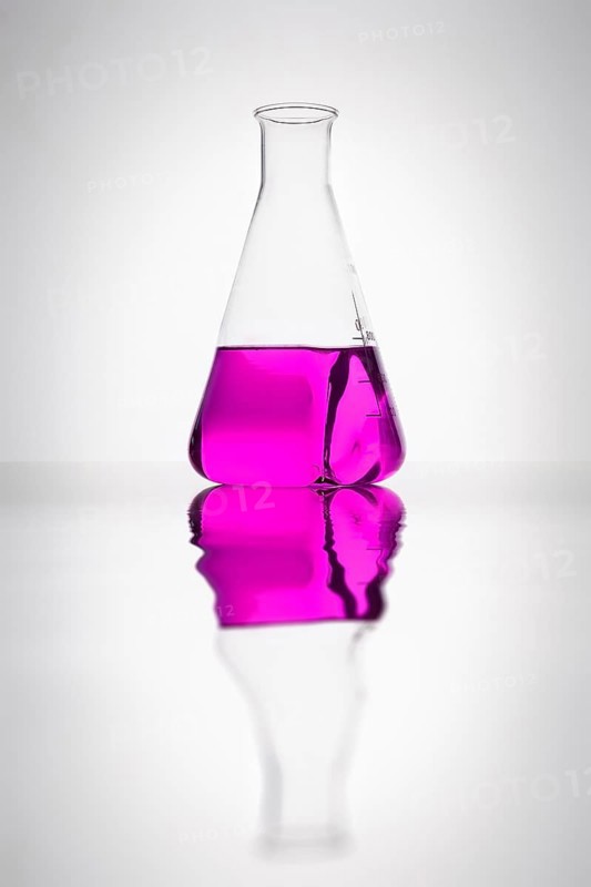 A glass bottle with purple liquid in a laboratory