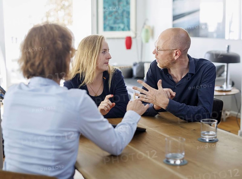 Symbolic photo on the subject of counselling. A young woman and a young man sit together at a table at home and receive counselling. Berlin, 13.08.2024