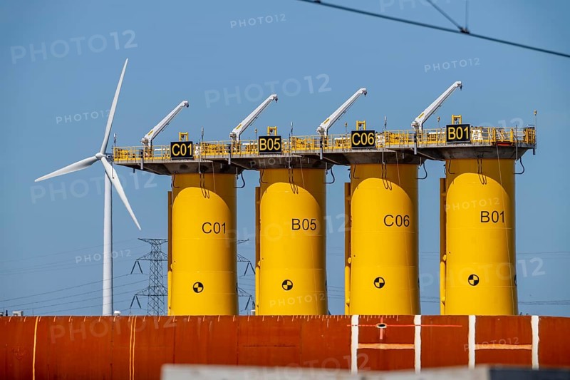 Transhipment centre for offshore wind turbines, which are transported here by the manufacturer and then shipped by special ships to the construction sites of the wind farms in the North Sea, here, yellow, so-called Transition Pieces Jackets, which are mounted on the monopile foundations driven into the seabed, on which the actual wind turbine is then mounted, in the port area of Vlissingen-Oost, Netherlands