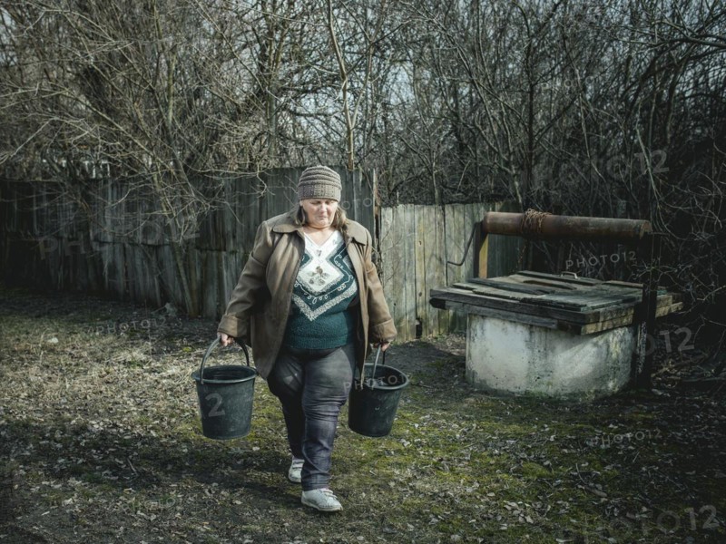 Larisa draws water from a well in Borshchivka. The village was under Russian occupation. She hid with her granddaughter Angelina in her house for almost six months, Borshchivka, Raion Isyum, Kharkiv Oblast, Ukraine, Europe