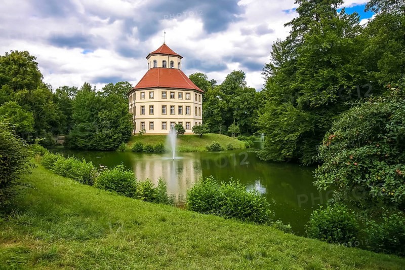 Oppenweiler moated castle, built in the 18th century, classicist style, castle complex in unequal-sided octagon, today town hall, architecture, tent roof with pavilion top, windows, lake, castle lake, water features, island, park, garden designer Friedrich Ludwig von Sckell, meadow, lawn, trees, bushes, shrubs, cloudy sky, Oppenweiler, Rems-Murr district, Baden-Württemberg, Germany, Europe