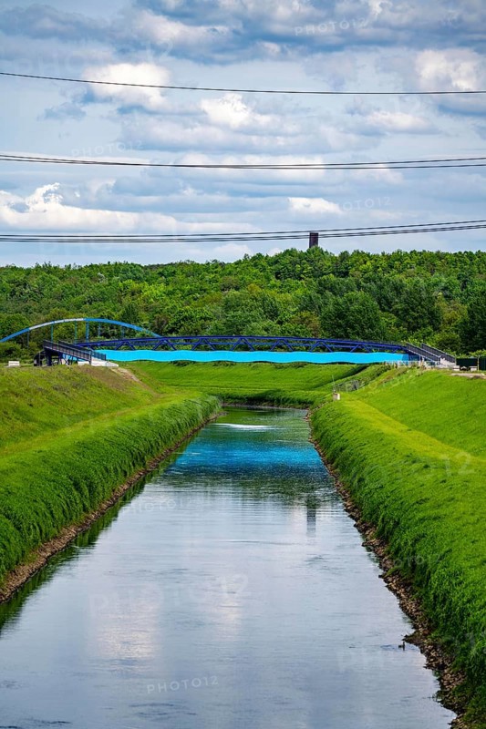 The Emscher at Essen-Karnap, with the Schurenbach spoil tip in the background, with the Bramme landmark for the Ruhr region, Emscher Island foot and cycle bridge, North Rhine-Westphalia, Germany, Europe
