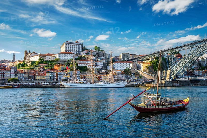 View of Porto city and Douro river with traditional boats with port wine barrels and sailing ship from famous tourist viewpoint Marginal de Gaia riverfront. Porto, Vila Nova de Gaia, Portugal, Europe