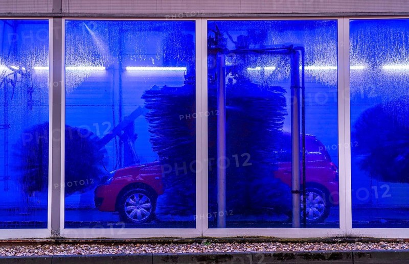 Car in an automatic car wash, car wash tunnel, cleaning foam is sprayed on, rotating brushes clean the vehicle