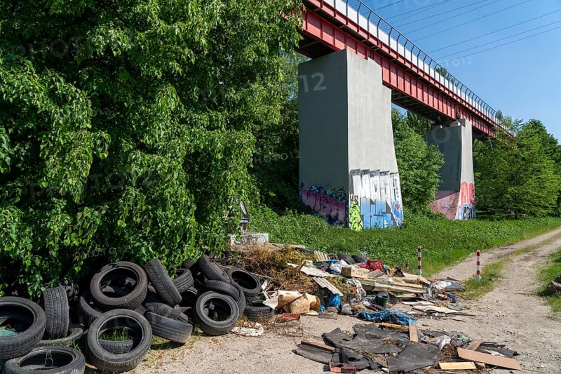 Illegally disposed waste, car tyres, building rubble, household waste, clothing, on a path next to a main road in Bochum, North Rhine-Westphalia, Germany, Europe