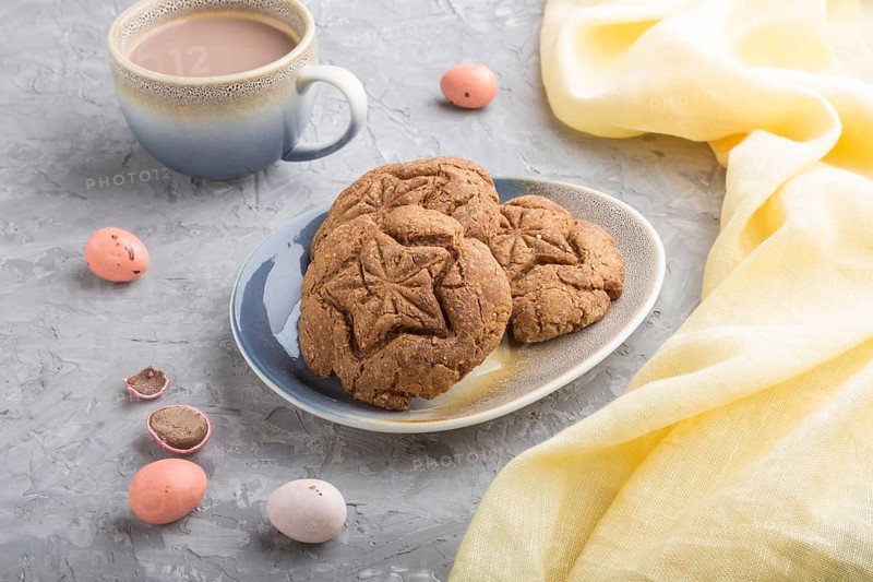 Homemade oatmeal cookies with a cup of cocoa and a yellow textile on a gray concrete background. side view, close up