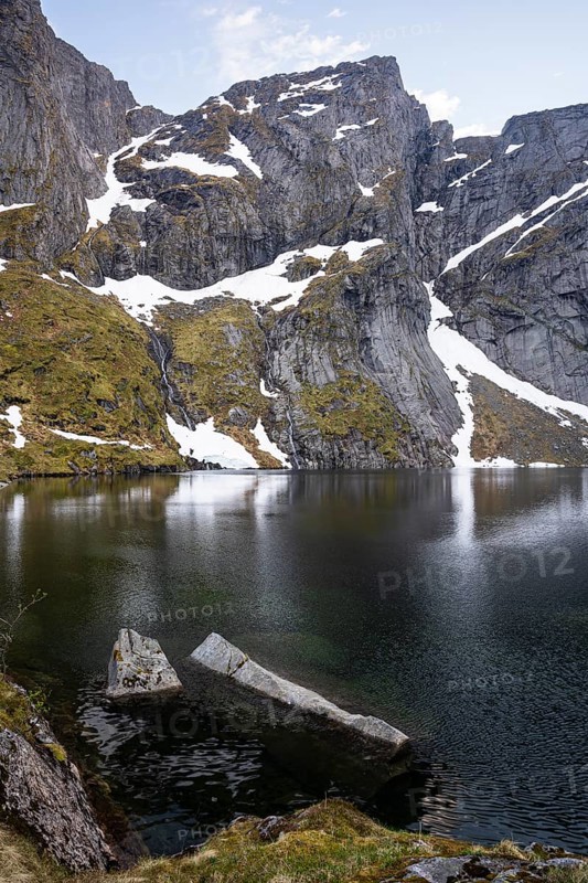 Lake Reinevatnet is located on the Reinebringen mountain. Rock faces with remnants of snow in early summer. Evening, good weather. Reine, Moskenesoya, Lofoten, Norway, Europe