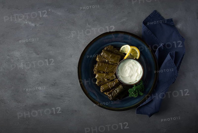 Dolma, cabbage rolls, grape leaves with filling, white sauce, lemon and herbs, rustic, selective focus, no people