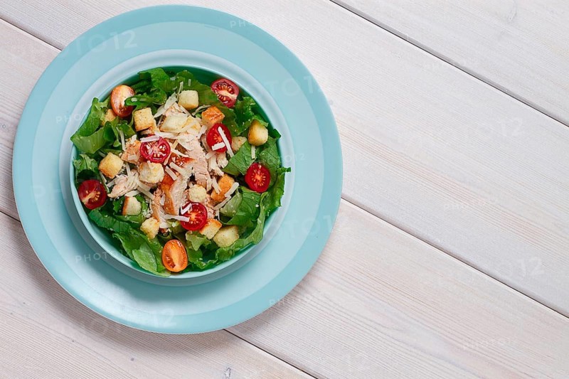 Classic Caesar salad, with cherry and croutons, top view, on a white table, horizontal, no people