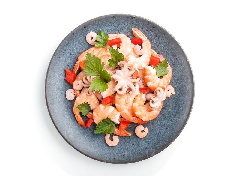 Boiled shrimps or prawns and small octopuses with herbs on a blue ceramic plate isolated on white background. top view, flat lay, close up
