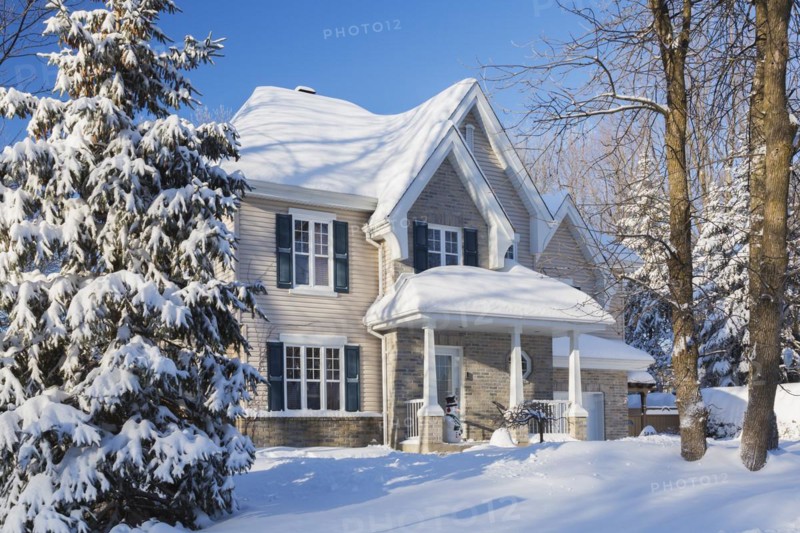 Country tan brick and vinyl cladded cottage style house facade with blue trim in winter, Quebec, Canada, North America