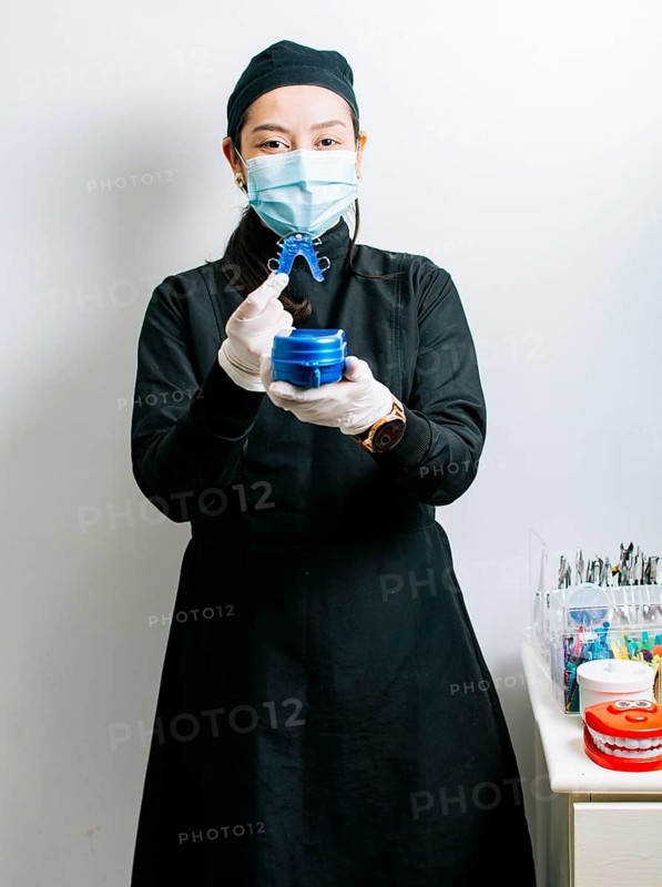 A dentist holding retainers, Female dentist holding dental retainers, Portrait of a female dentist holding retainers